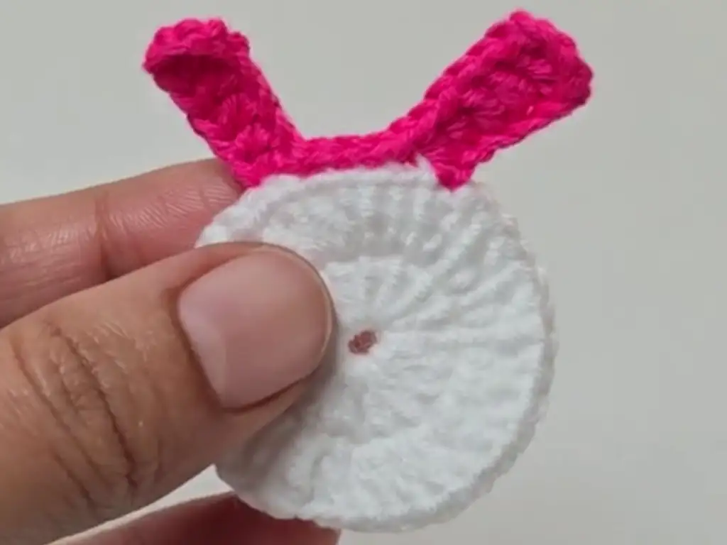 In this image, a hand holds a single adorable crochet bunny keychain tutorial piece.