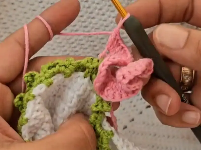 Forming rose petals with pink yarn for the flower blanket
