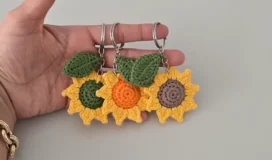 hand holding colorful crochet sunflower keychains with green leaves