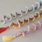 Three colorful crochet wind spinners with tassels, laid flat on a table – easy spiral crochet DIY decoration.