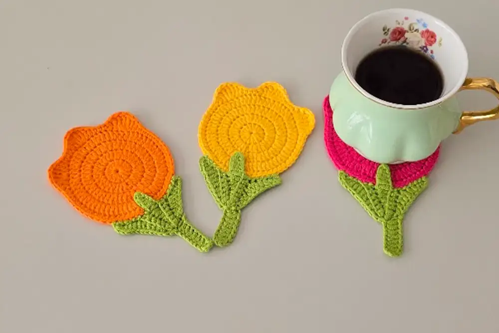 Two tulip coasters in orange and yellow with a coffee cup on top