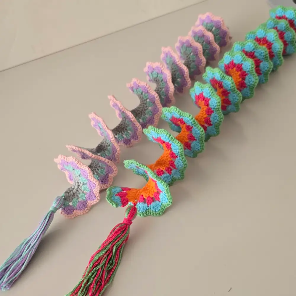 Two colorful crochet wind spinners with tassels, laid flat