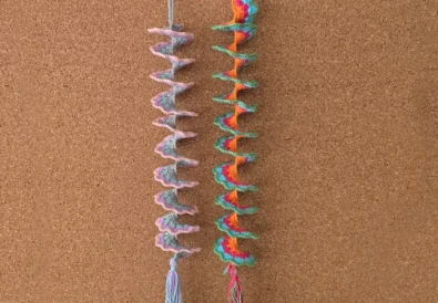 Two crochet wind spinners pinned to a cork board display