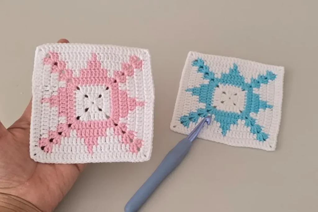 hand holding a pink easy crochet granny square with blue square placed below