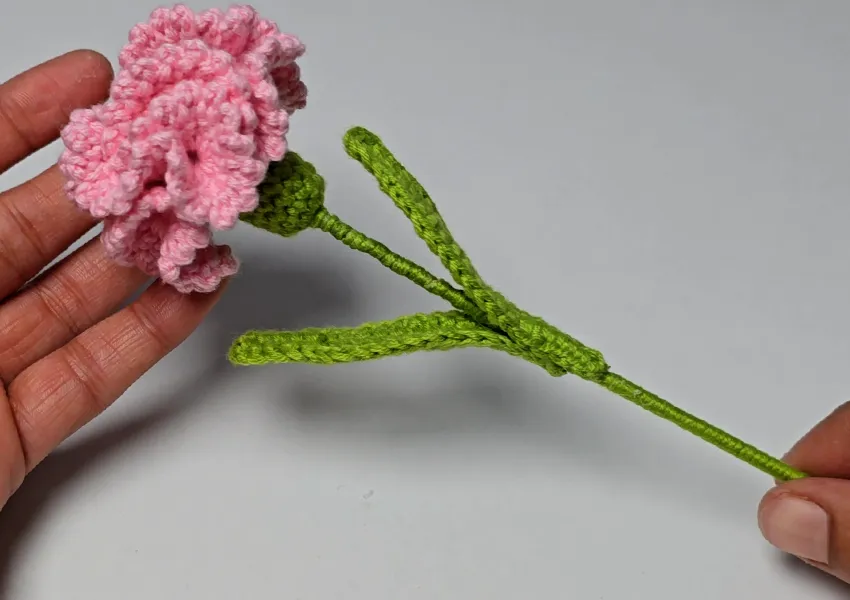 final assembly of the crochet carnation flower with stem and leaves attached