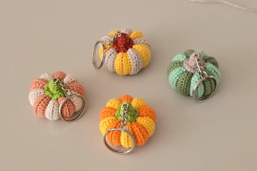 Collection of crochet pumpkin keychains in various colors arranged on a table