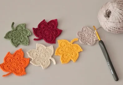 Crochet maple leaf pattern in autumn colors with yarn and hook.