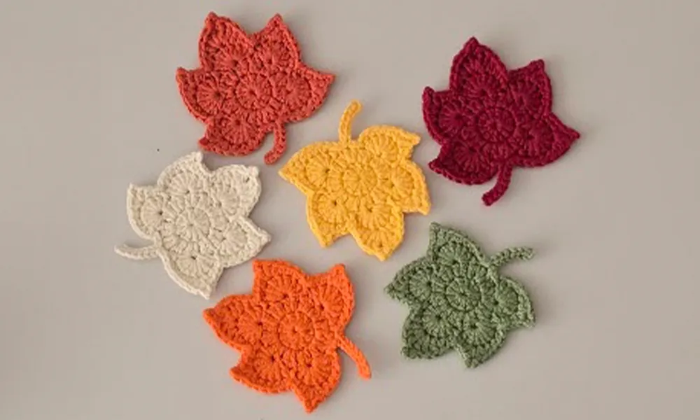 Set of crochet maple leaves in red, green, yellow, and cream.