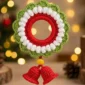 crochet wreath christmas ornament with bells in red, green, and white