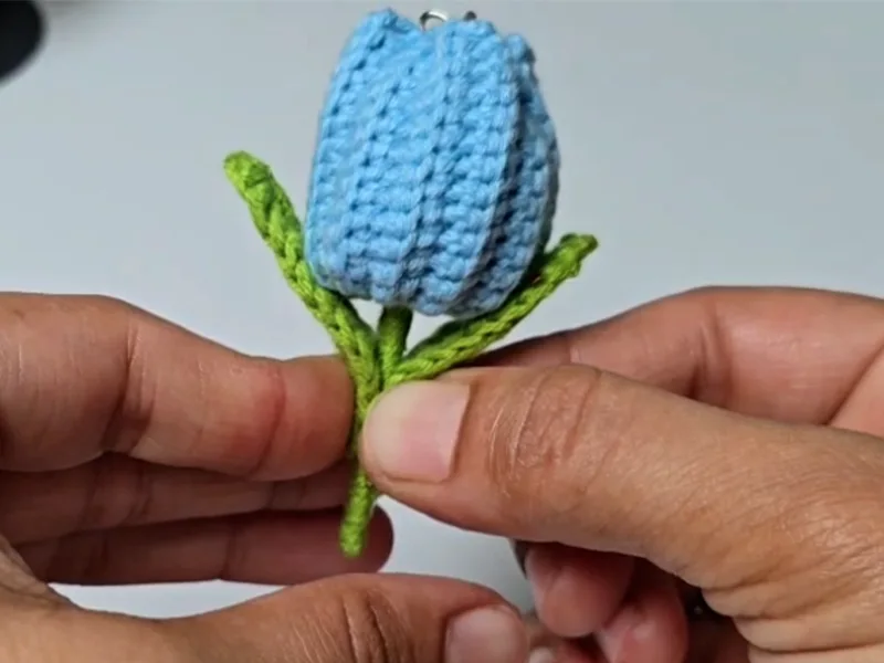 Easy crochet tulip keychain in blue held in hands