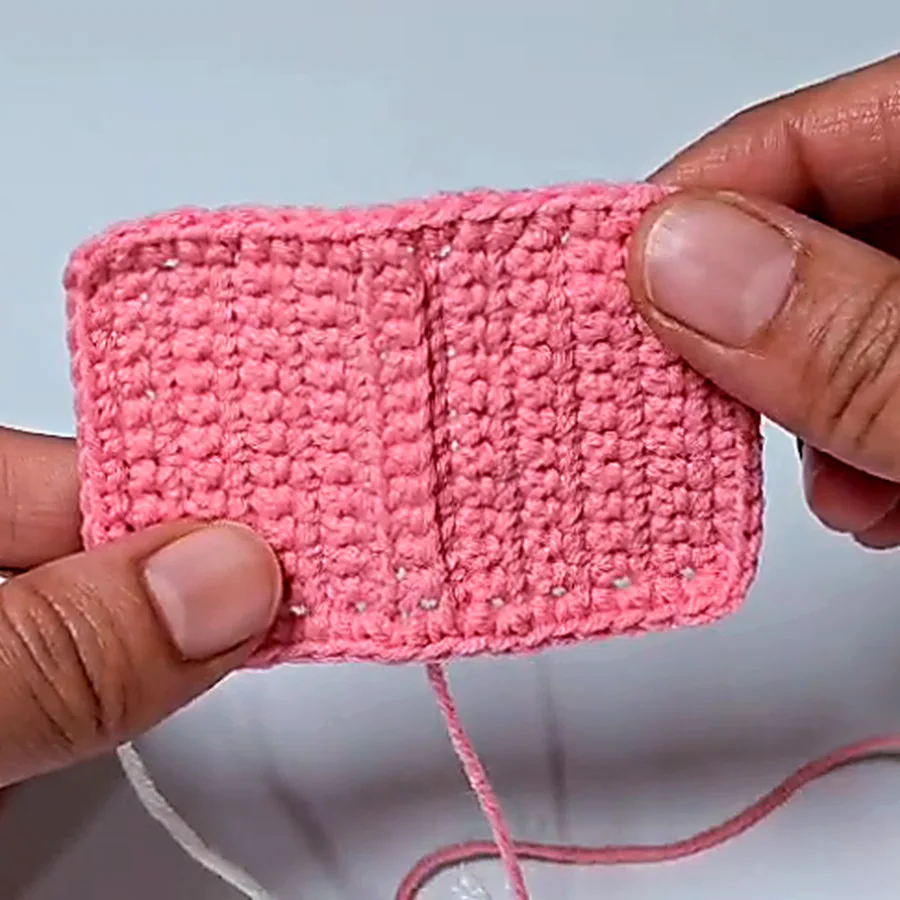 Unfolded crochet book keychain cover panel in pink yarn, showing the flat cover piece before folding.