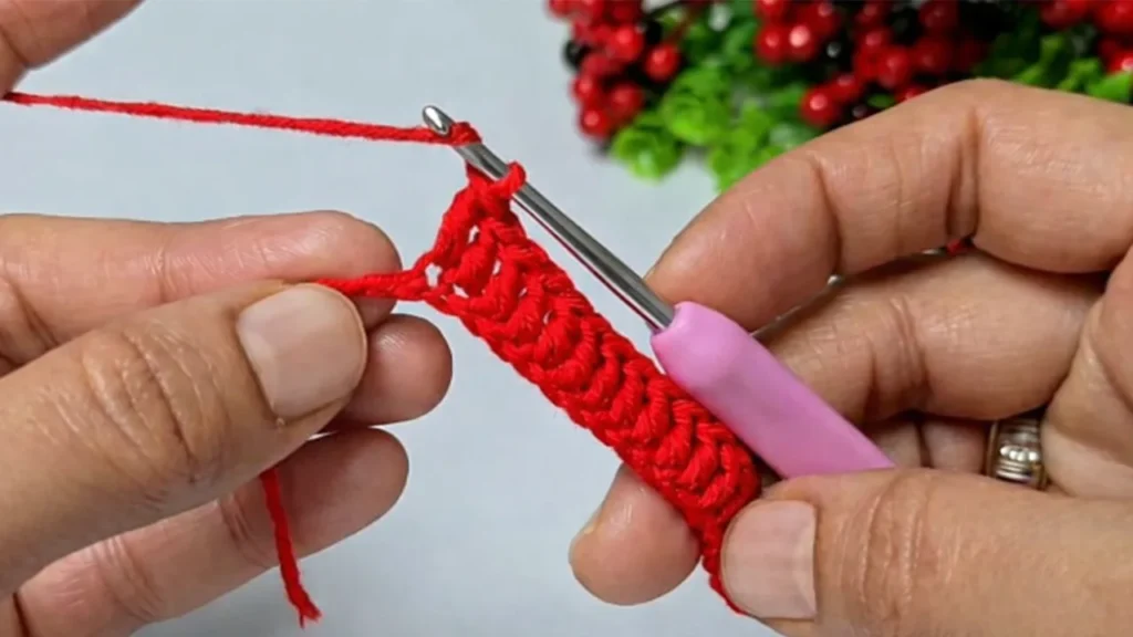 Starting the crochet mini gift bag with a magic ring using red yarn and a crochet hook
