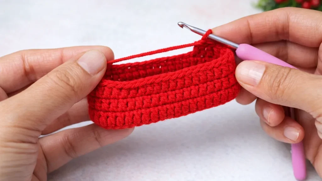 Crochet mini gift bag pouch body being worked with red yarn and a crochet hook