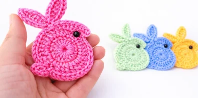 Easy crochet bunny applique for beginners held in hand with colorful crochet bunnies in background