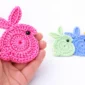 Easy crochet bunny applique for beginners held in hand with colorful crochet bunnies in background