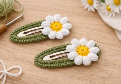 Crochet snap hair clip with daisy flower made using beginner-friendly pattern on neutral background