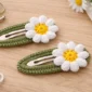 Crochet snap hair clip with daisy flower made using beginner-friendly pattern on neutral background