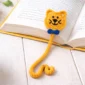 easy crochet cat bookmark pattern with curly tail and blue bow inside an open book, beginner friendly DIY crochet gift idea