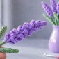 Easy crochet lavender flower held by hand with lavender bouquet in vase on soft blurred background