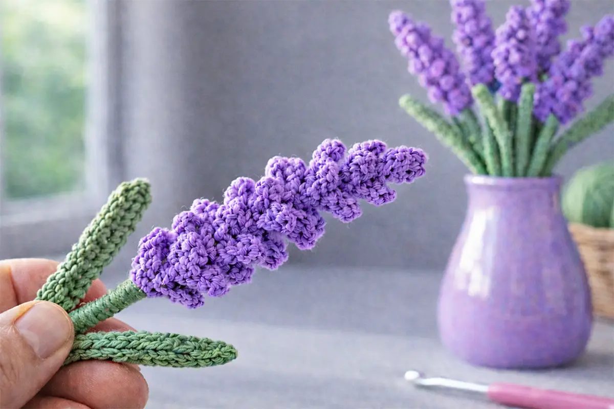 Easy crochet lavender flower held by hand with lavender bouquet in vase on soft blurred background