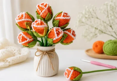 Easy crochet rosebud pattern made from a flat circle with orange yarn, white edge detail, green leafy base, and a handmade bouquet look.