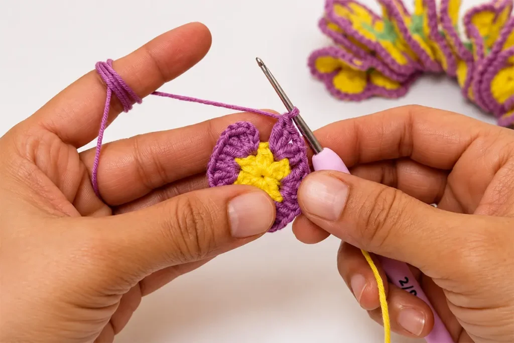 Hands crocheting the flower decoration for an easy crochet wind spinner pattern using purple and yellow yarn