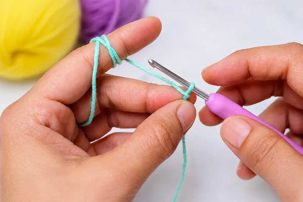Hands starting a crochet wind spinner foundation chain with mint yarn and a crochet hook for an easy beginner pattern