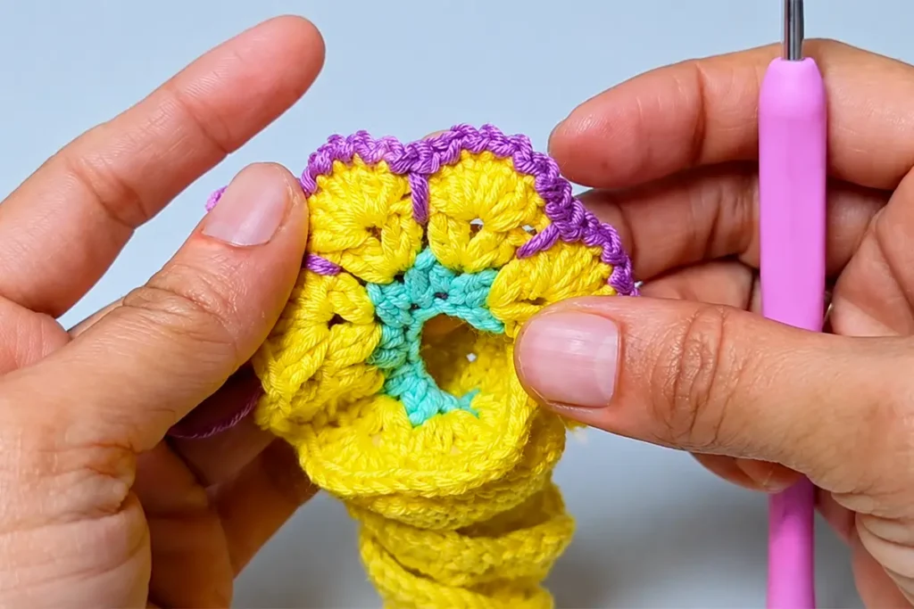 Close-up of adding the textured edge to an easy crochet wind spinner pattern with yellow, mint, and purple yarn.