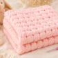 Easy crochet stitch pattern that looks woven, shown as a soft folded baby blanket with a textured white crochet design.