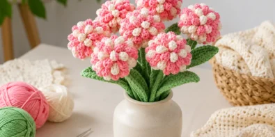 Realistic crochet flower bouquet in a small vase with cotton yarn balls and crochet hook on a clean craft table
