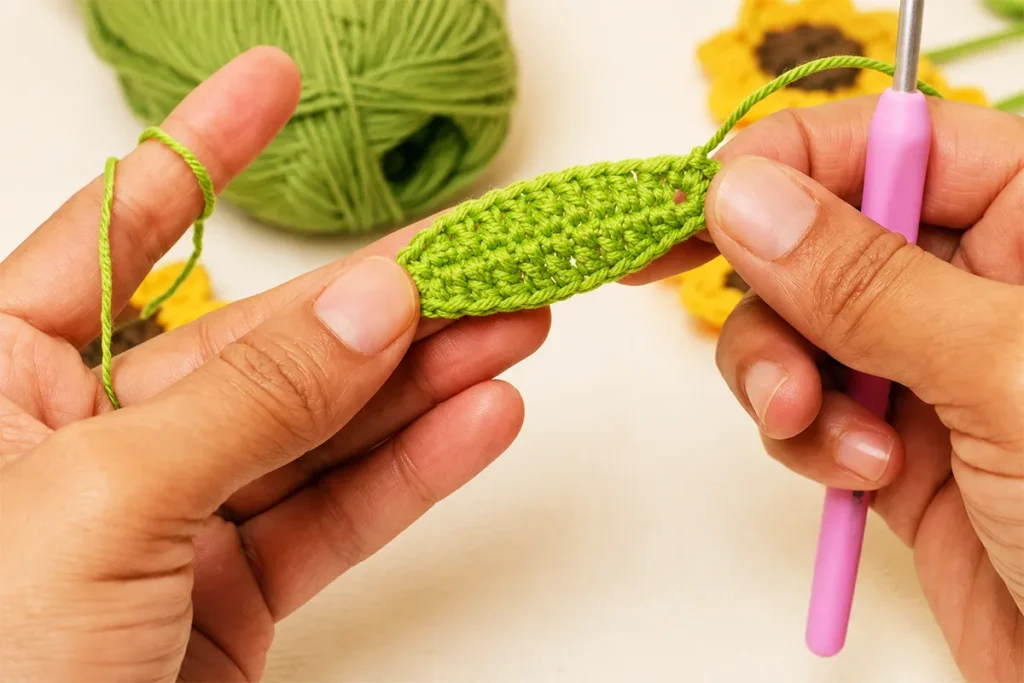 Hands holding a finished green crochet leaf for a realistic crochet sunflower pattern