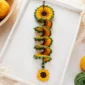 Crochet sunflower wind spinner pattern styled on a tray with yarn and crochet hook