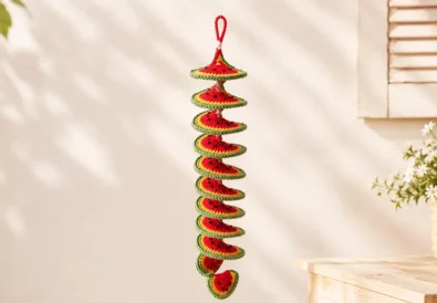 Crochet watermelon wind spinner featured image showing a finished spiral crochet decoration with a watermelon slice charm on a soft pastel craft table