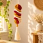 Three-color crochet wind spinner hanging in a warm boho-style room with a yellow bead and white tassel.